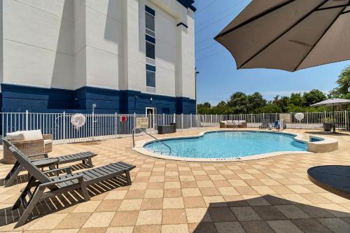 uma piscina com bancos e um guarda-sol ao lado de um edifício em Evoke Destin Hotel em Destin