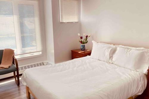 a bedroom with a white bed and a vase of flowers at Unit #201 Cozy Mountain View 1BR in DT in Canmore