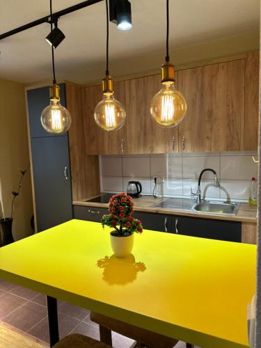 a yellow table in a kitchen with lights at ORA-PRN,peaceful central apartment in Pristina