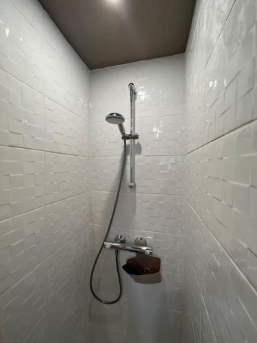 La salle de bains est pourvue d'une douche et d'un mur carrelé blanc. dans l'établissement Appartement 3 pièces moderne 2 à 6 personnes, à La Bourboule