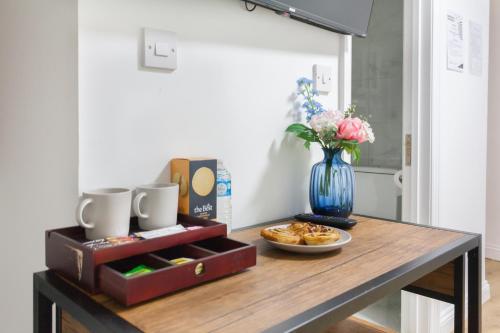 a table with a plate of food and a vase of flowers at Holloway Apartments in London