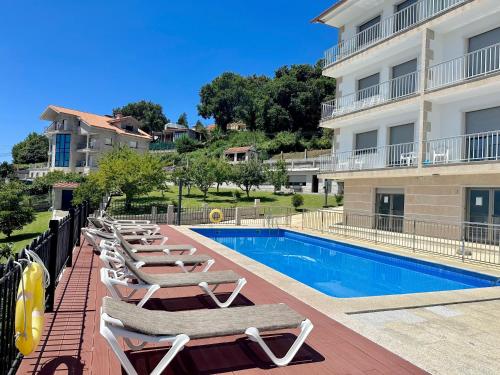 a row of chaise lounge chairs next to a swimming pool at Apartamentos Canada in Raxó