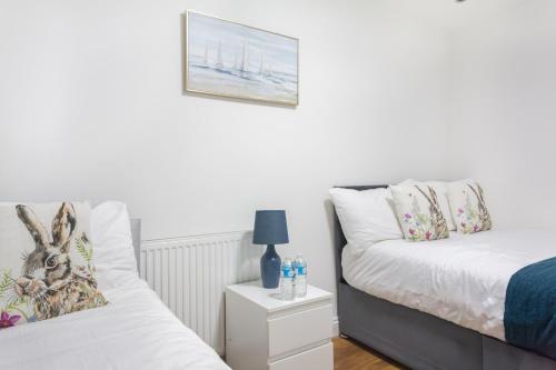 a bedroom with two beds and a night stand with a lamp at Holloway Apartments in London