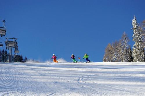 a group of people skiing down a snow covered slope at Hotel Castel Latemar in Carezza al Lago