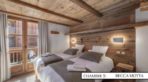 deux lits dans une chambre aux murs en bois dans l'établissement Chalet K120 - Village du Praz - Courchevel, à Courchevel
