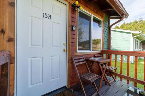 a porch with a white door and a wooden chair at Elk Meadow Cabins 15B Lady Bird - Single Room in Orick