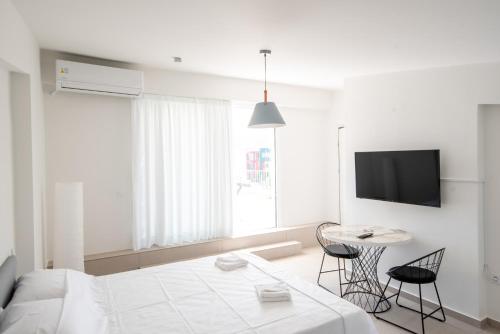 Habitación blanca con cama, mesa y TV. en Ennea Suites-Null suite, en Flámbouras