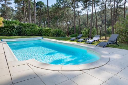 une piscine avec deux chaises longues à côté dans l'établissement villa piscine chauffée 10pers dans cadre exceptionnel-AG19, à Lacanau