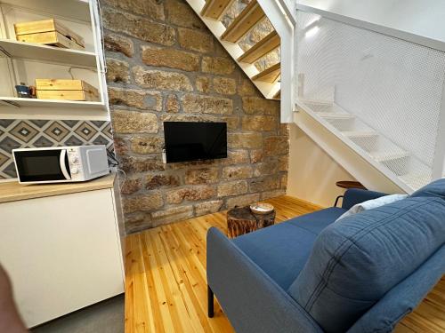 a living room with a blue couch and a stone wall at Le Gemelle Diverse in Cinisi