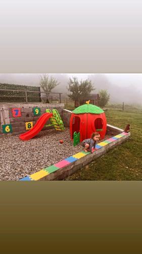 a child playing in a playground with an umbrella at Seosko domacinstvo Becirovic - Kukulik lodgings in Bijelo Polje