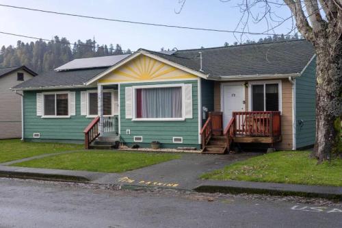 a green and yellow house with a porch at Elk Meadow Cabins 17B Gold Rush - Single Room in Orick