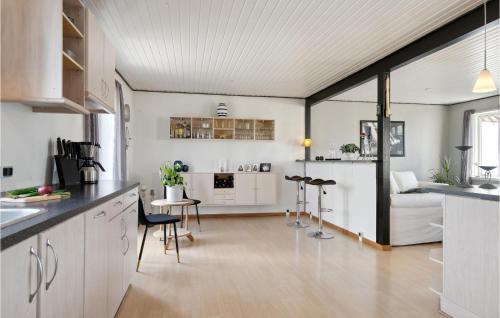 FarsøにあるBeautiful Home In Farsø With Kitchenのキッチン、リビングルーム(白いキャビネット、テーブル付)