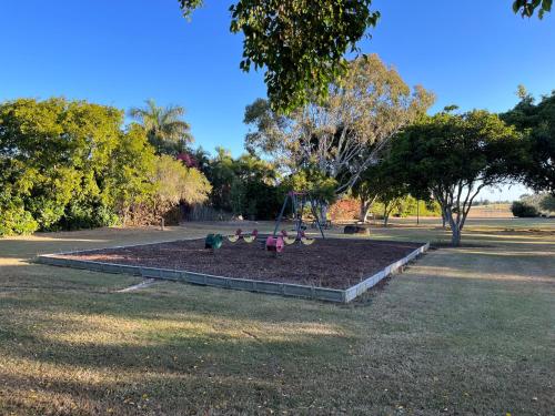 a park with a playground with two children on a swing at Beach Shack in Bargara in Bargara