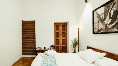 a bedroom with a white bed and a wooden door at Hotel Sin Nombre in Oaxaca City