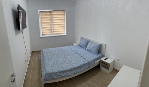 a bedroom with a bed with blue sheets and a window at Dream Accommodation in Chiajna
