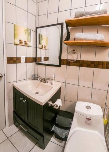 a bathroom with a sink and a toilet and a mirror at Casa Girasol Tulum in Tulum
