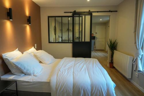 1 dormitorio con cama blanca y espejo en la pared en Appartement Saint-Valery, en Saint-Valery-sur-Somme
