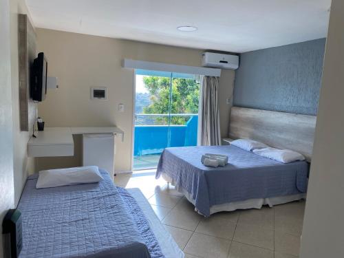 a hotel room with two beds and a window at Pousada Mirante da Prainha in Arraial do Cabo