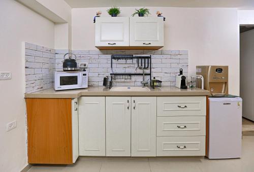 a kitchen with white cabinets and a microwave at Tony Guesthouse in Acre