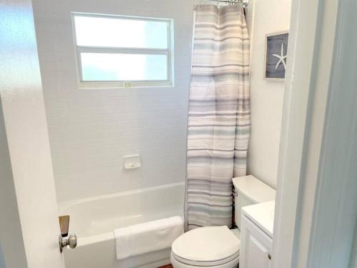 a white bathroom with a toilet and a window at Modern Apartment - 4 of 4 in Punta Gorda