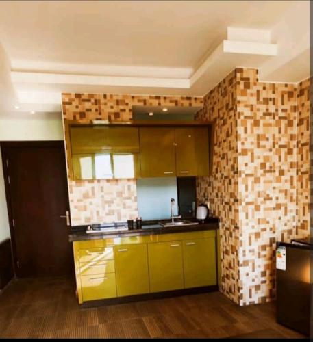 a kitchen with yellow cabinets and a brick wall at Seven stars hotel apartment in Amman