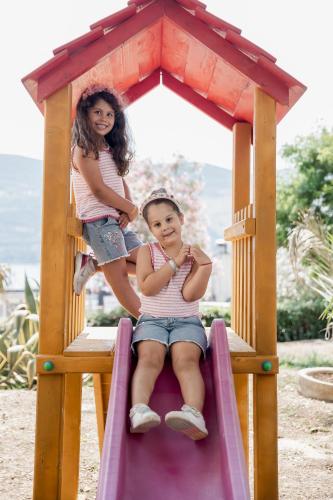 two girls sitting on a slide at a playground at HOTEL TALIA in Herceg-Novi