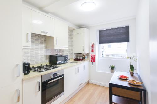 a kitchen with white cabinets and a stove top oven at Holloway Budget Apartment - 1 Minute to Emirates Stadium - Next to Station - City Center in London