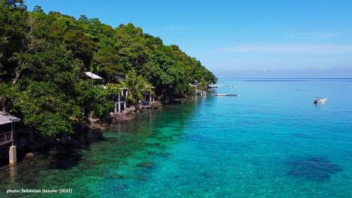 an island with trees and a boat in the water at Santi Garden Bungalows in Iboih