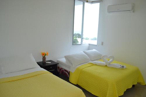 sypialnia z 2 łóżkami z żółtą pościelą i oknem w obiekcie Edificio Galatea w mieście Manta