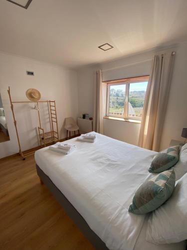 1 dormitorio con 1 cama blanca grande y ventana en Like a Local Guest House, en Ericeira