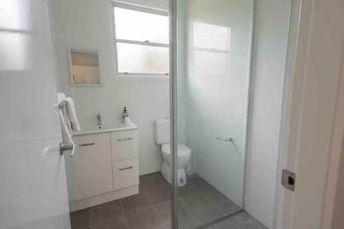 a bathroom with a shower and a toilet and a sink at Garden-nestled granny flat between winery and town in Armidale