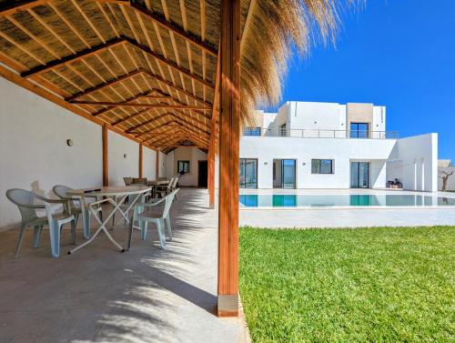a patio with a table and chairs in front of a house at Villa AZMIR Djerba in Arkou