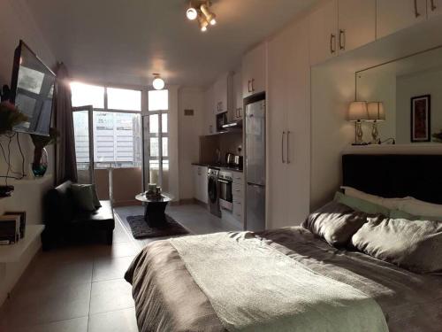 a bedroom with a large bed and a kitchen at 36 HydePark Apartments in Cape Town