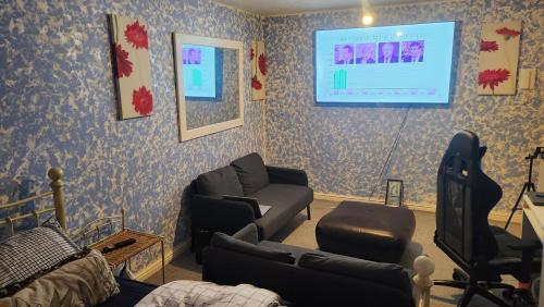 een woonkamer met een bank en een tv aan de muur bij Moris Lodge in Hither Green