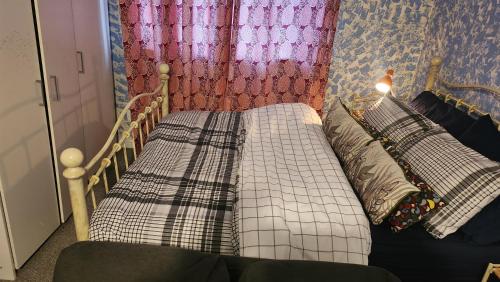 2 aparte bedden in een kamer met een gordijn bij Moris Lodge in Hither Green