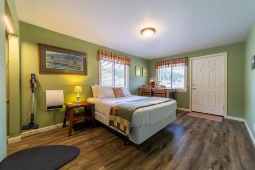 a bedroom with a bed with green walls and wooden floors at Elk Meadow Cabins 19B Johnny Redwood - Single Room in Orick