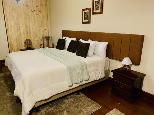 Un dormitorio con una cama grande con sábanas y almohadas blancas. en Pousada Miraflores, en Campos do Jordão