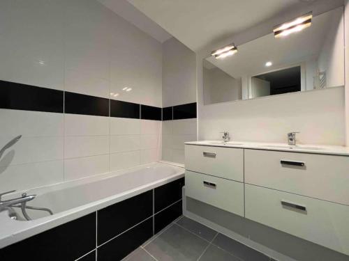 La salle de bains blanche est pourvue d'une baignoire, d'un lavabo et d'une baignoire. dans l'établissement App Le Golf T3 terrasse wifi pkg, à Béziers