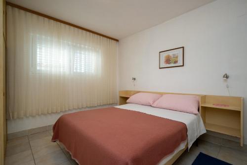 una camera da letto con un letto con cuscini rosa e una finestra di Apartments with a parking space Povljana, Pag - 227 a Povljana (Pogliana)