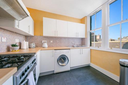 a kitchen with white cabinets and a washer and dryer at Castle Street Apartments ✪ Grampian Lettings Ltd in Aberdeen