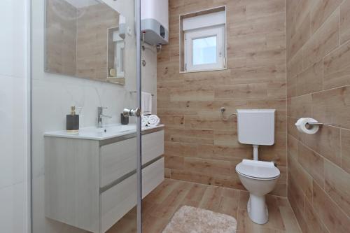 Un baño con inodoro, lavabo y espejo. en Apartment Pag 6412b, en Pag