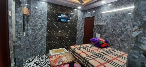 1 dormitorio con cama y pared de piedra en Aggarwal luxury room with private kitchen washroom and balcony along with fridge, Ac, Android tv, wifi in main lajpat nagar en Nueva Delhi