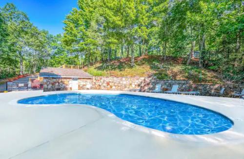a swimming pool in a backyard with a stone wall and trees at Baileys Mountain Retreat in Gatlinburg