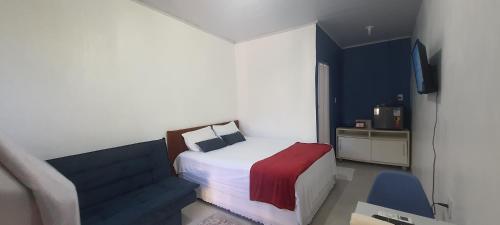 a small bedroom with a bed and a chair at Hospedaria Salém in Soure