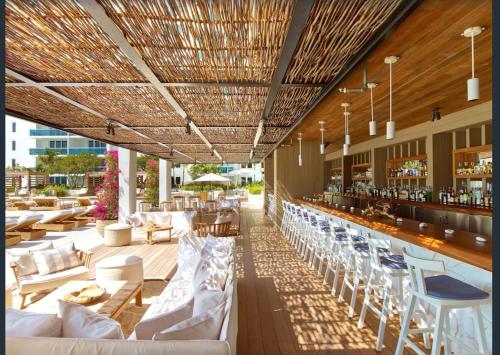 a restaurant with white chairs and a bar at 1 Hotel & Homes Miami Beach Oceanfront Residence Suites By Joe Semary in Miami Beach