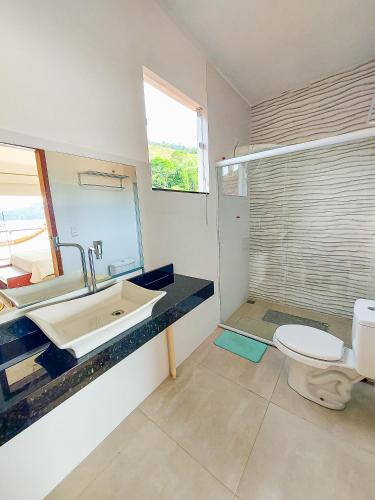 a bathroom with a sink and a toilet and a mirror at Casa Beira Mar Angra in Angra dos Reis