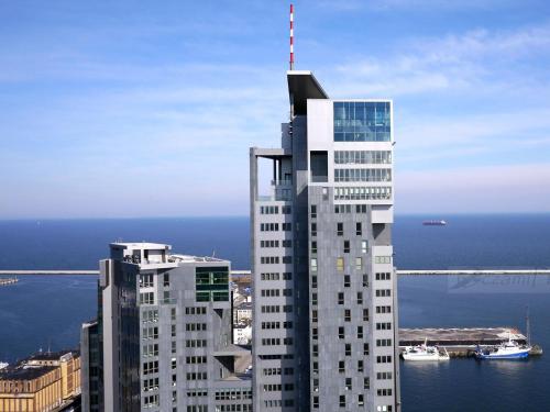 a tall white building with a antenna on top of it at Apartamenty Sea Towers in Gdynia