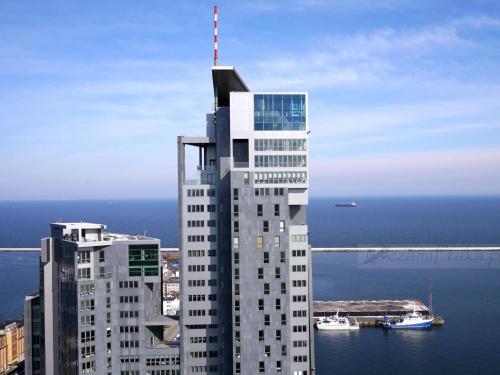 un edificio blanco alto junto a un cuerpo de agua en Apartamenty Sea Towers, en Gdynia