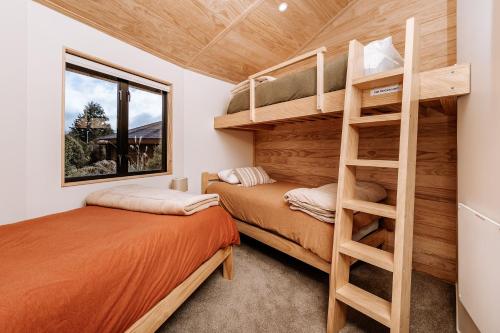 two bunk beds in a small room with a ladder at Kaho - Ohakune Holiday Home with Spa in Ohakune