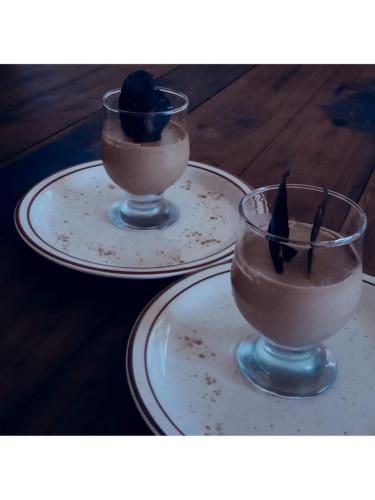 two glasses of chocolate pudding sitting on plates at L'anis Etoilé - Hôtel Restaurant in Antsirabe